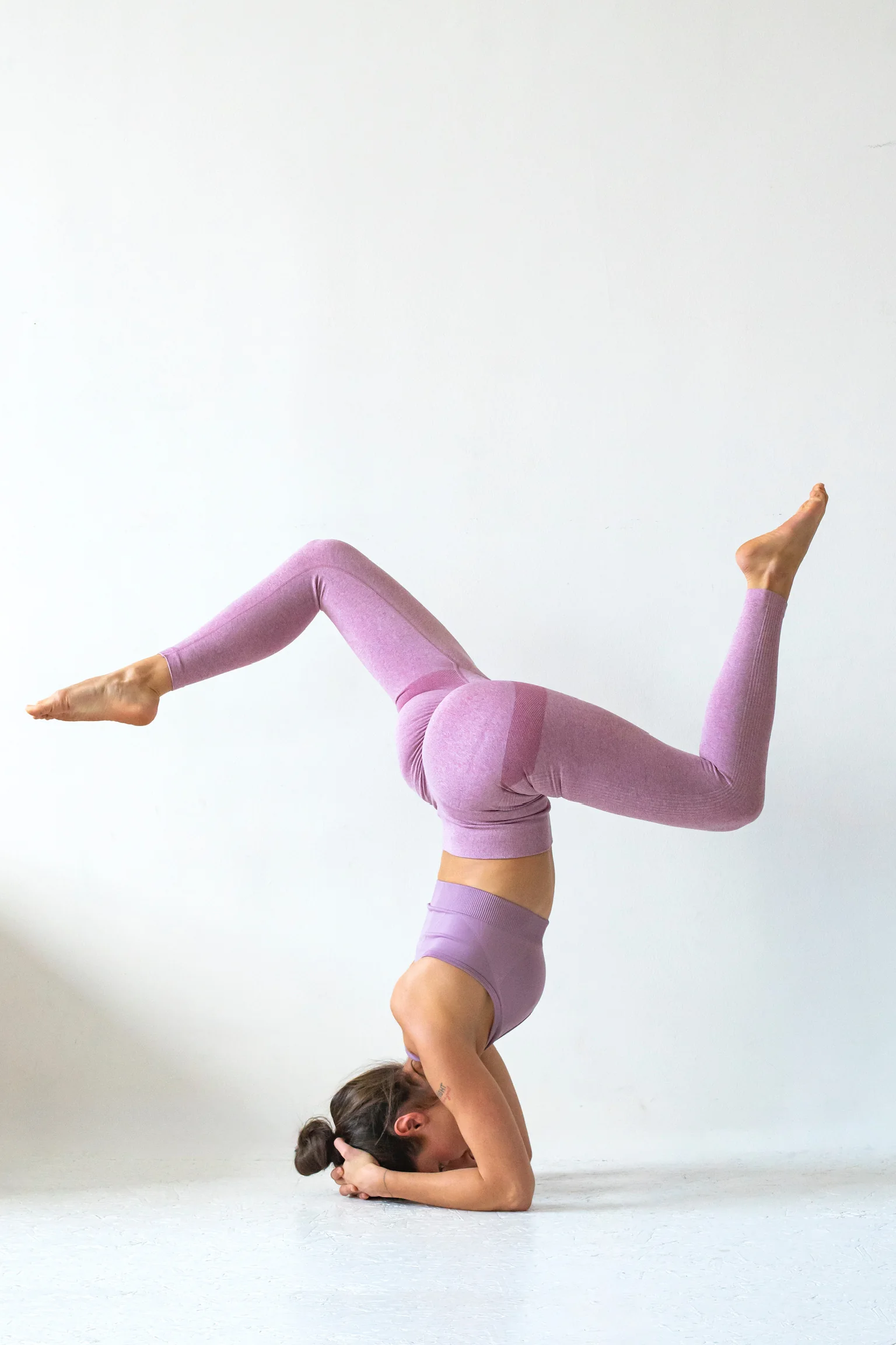 Marie Lamy en posture de yoga inversée sur fond clair.